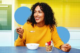 a photo of a woman eating yogurt with nuts and berries while sitting at a kitchen table