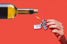 a photo of a hand holding a lighter to a wine bottle with a cork