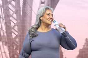 an older woman drinking a bottle of water while on an outdoor walk