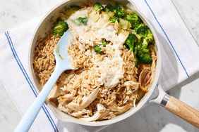 overhead view of broccoli, creamy mixture, chicken, and brown rice in a pan, unmixed