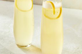 Two champagne glasses with lemonade mimosas garnished with a lemon peel
