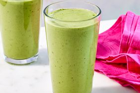 two tall pint glasses filled with green smoothie next to hot pink napkin