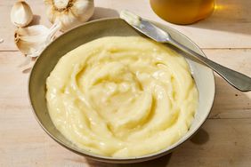 The best homemade aioli recipe in a bowl, with a garlic head in the background