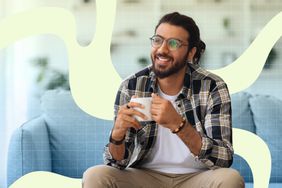 a photo of a man holding a mug of tea while sitting on a couch
