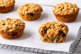 Five breakfast peanut butter-chocolate chip oatmeal cakes, the one in the front halved with a dollop of peanut butter showing filling showing