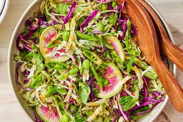 Cabbage & Edamame Salad with Peanut Dressing tossed in a bowl with utensils