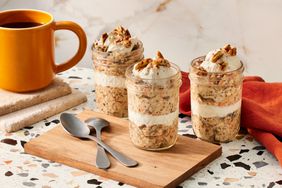 three small jars of carrot cake overnight oats, two spoons, a cloth napkin and a cup of coffee