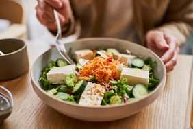 a photo of a person having a salad with pieces of tofu in it