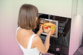a photo of a woman warming up her food in the microwave