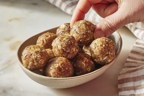 hand picking up a Peanut Butter-Oat Energy Ball out of a bowl 