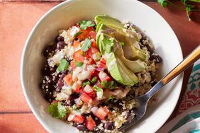 Overhead view of a white bowl of Black Bean-Quinoa Bowl recipe on a reddish brown tile tabletop