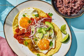 Huevos Divorciados on a plate with a bowl of refried black beans to the side. 