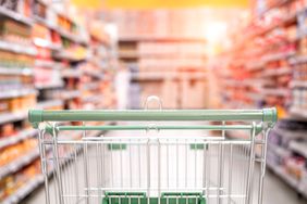 a photo of an empty grocery cart going down a snack food isle 