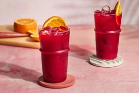 Ginger-beet juice in a tall glass with a slice of orange