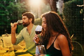 a photo of a woman sniffing a glass of red wine before having a sip