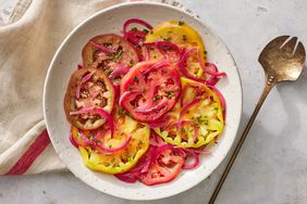 Overhead view of a rustic off-white plate of Heirloom Tomato Salad with Pickled Onions recipe