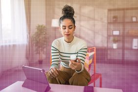 a photo of a woman sitting a chair in front of her tablet while looking at the back of a bottle of supplements