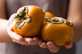 hands holding persimmons