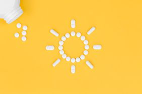 a photo of Vitamin D supplements arranged into a shape of a sun with a bottle pouring out some pills