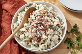 Overhead view of a white bowl with a wooden spoon of Loaded Cauliflower Salad recipe