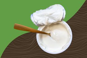 Cup of plain greek yogurt with a gold spoon on a green and brown background