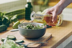 a photo of someone pouring a bottle of olive oil over a bowl of salad