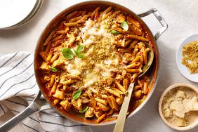 One-pan chicken parmesan pasta, topped with fresh basil and with a serving spoon scooping up pasta on the right side of the skillet