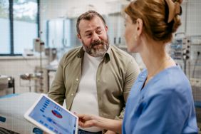 a photo of a man speaking to his doctor while they go over his results