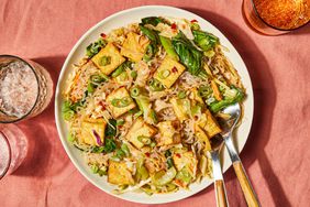 Shirataki noodles with tofu & veggies in a white bowl, with utensils on the right side