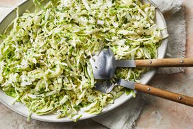 A platter of Simple Cabbage Salad on pink stone surface with serving utensils.
