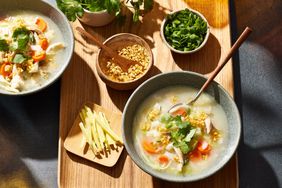 High angle photo of 2 bowls of Thai-Style Chicken & Rice Soup with Fried Garlic Oil and toppings