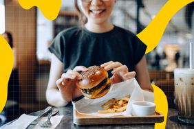 a photo of a woman eating a burger and french fries at a restaurant