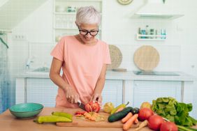 a photo of a woman chopping vegetables in her kitchen to make a salad 