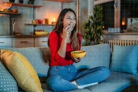 a photo of a woman having a snack on the couch
