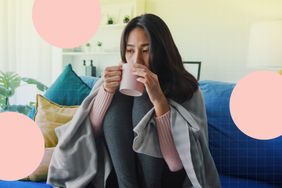 a photo of a woman sitting on a couch, wrapped in a blanket, while sipping on tea