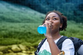 a photo of a woman drinking electrolytes during a hike