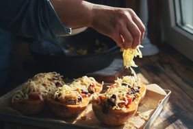 a photo of a person placing pre-shredded cheese onto a vegetable