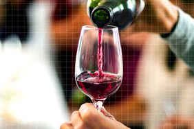 Cropped Hands Pouring Red Wine In Wineglass