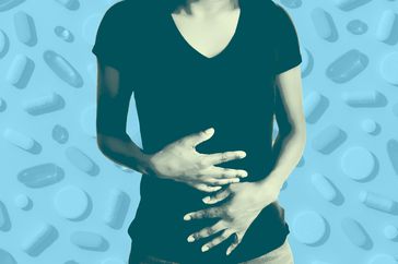 a photo of a woman grabbing her stomach with various types of supplements in the background