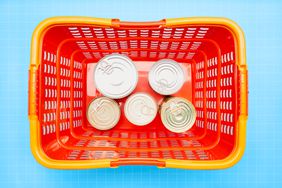 a photo of a grocery basket with canned food it in 
