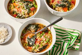 High angle shot of 3 bowls of Vegetable Noodle soup on a light surface with striped linen