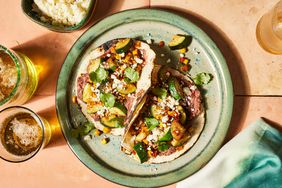 Two vegetarian tacos with zucchini & corn on a green ceramic plate