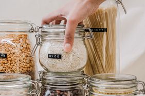 a person holding a labelled jar of rice with other labelled jars