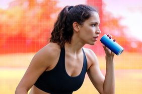 a photo of a woman drinking an energy drink while exercising