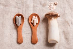 a photo of mushroom supplements on wooden spoons alongside a mushroom with an open capsule above it