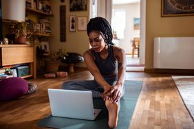 woman doing yoga with laptop at home