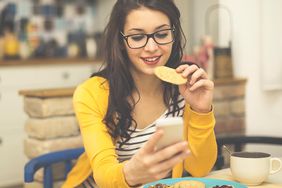 woman eating on her phone